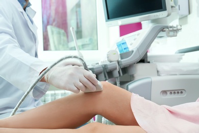 Photo of Doctor conducting ultrasound examination of knee joint in clinic, closeup