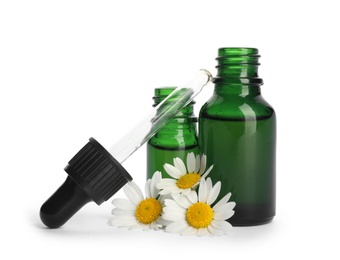 Photo of Chamomile flowers and cosmetic bottles of essential oil on white background