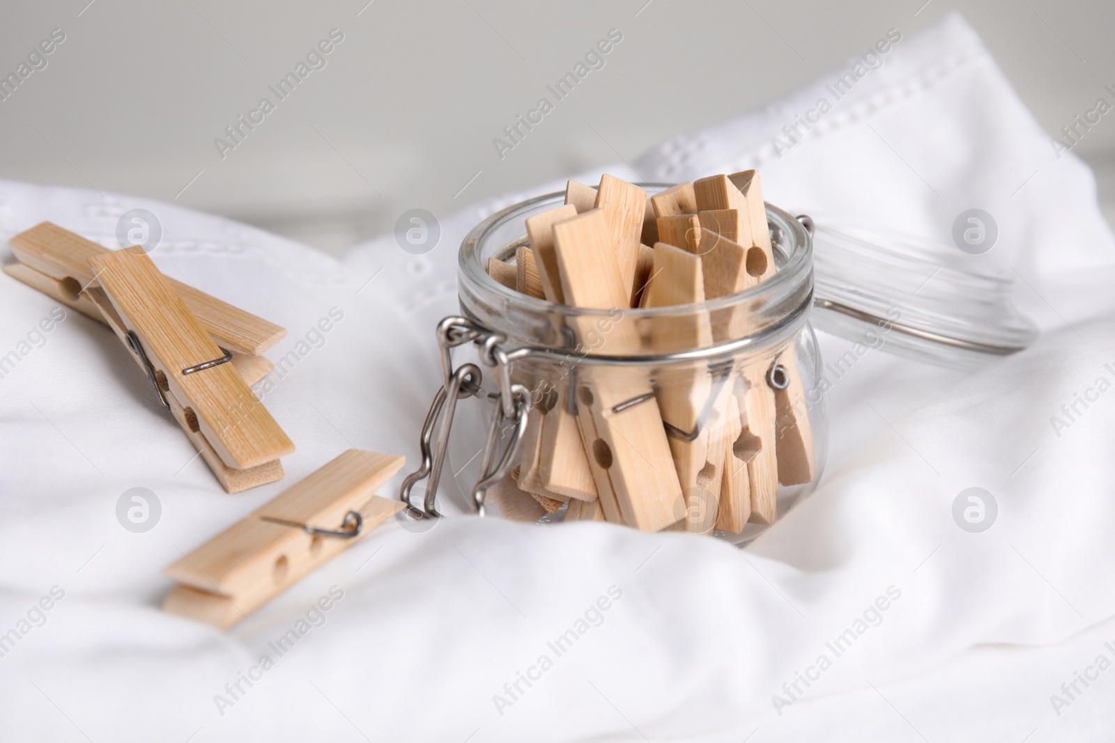 Photo of Many wooden clothespins and glass jar on white shirt