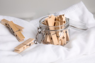 Photo of Many wooden clothespins and glass jar on white shirt