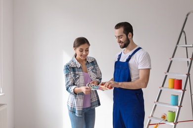 Photo of Male decorator and young woman with color palette indoors
