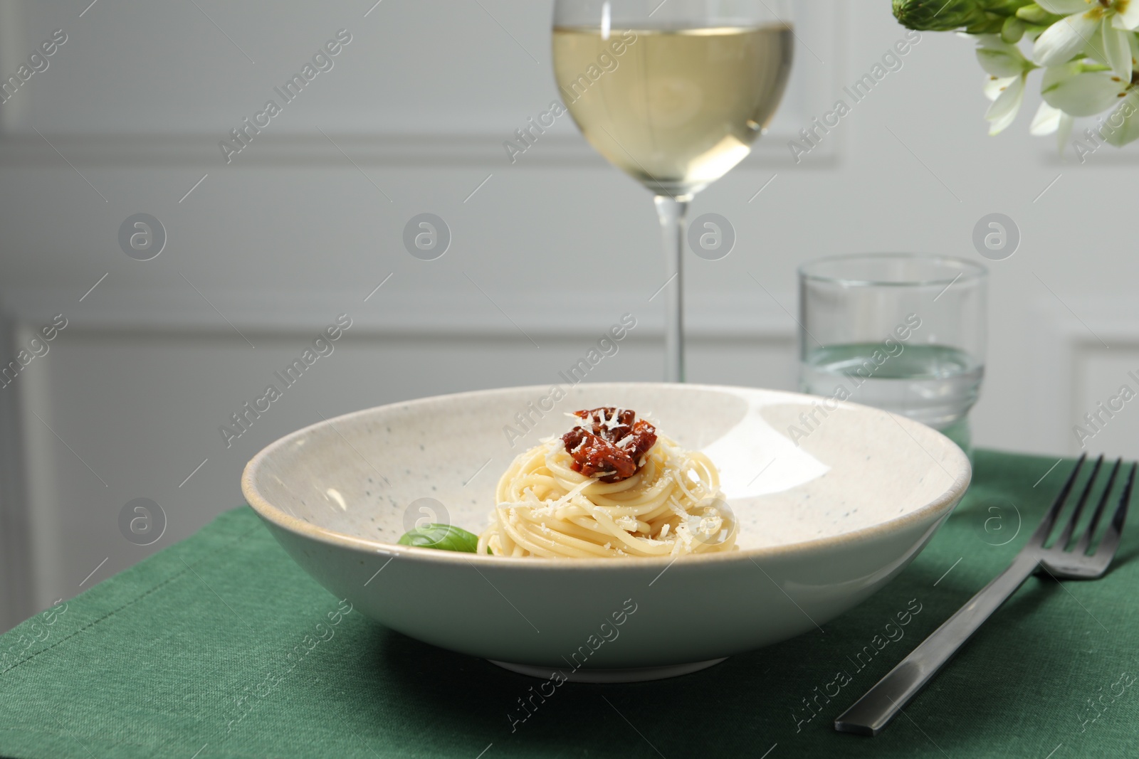 Photo of Tasty spaghetti with sun-dried tomatoes and parmesan cheese served on table, closeup. Exquisite presentation of pasta dish