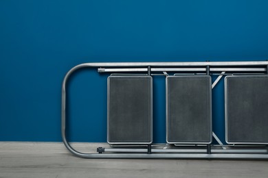 Metallic folding ladder near blue wall indoors