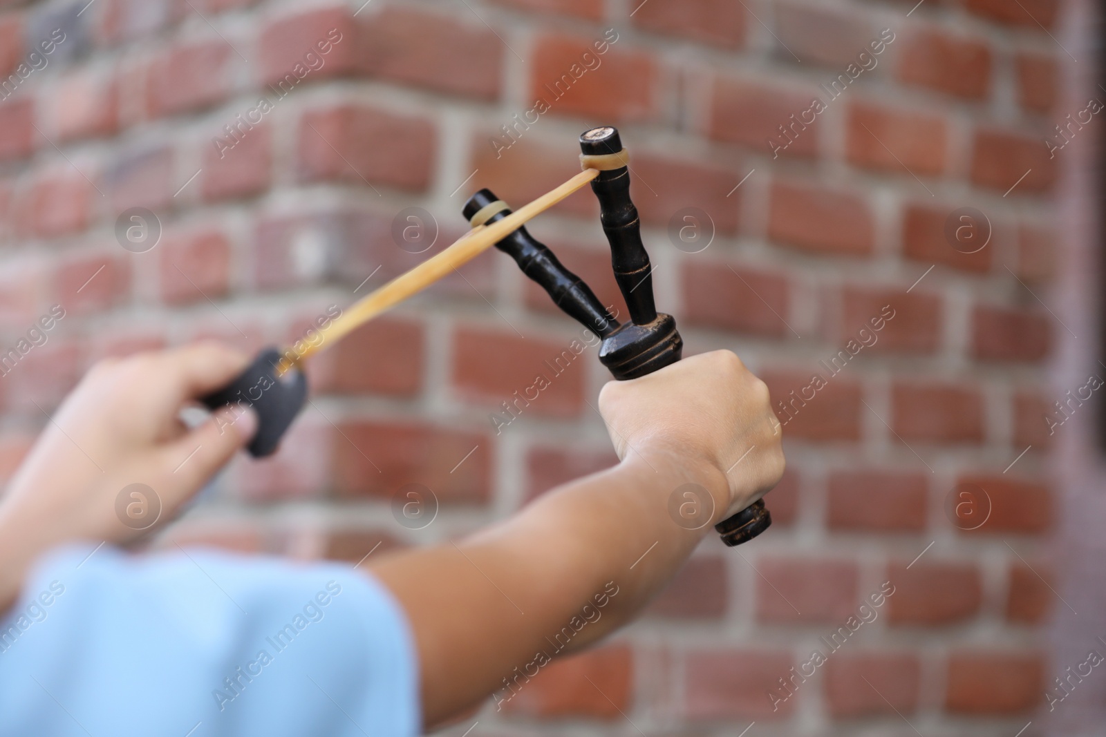 Photo of Little boy playing with slingshot outdoors, closeup