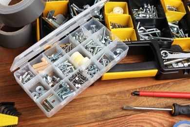 Photo of Boxes with different furniture fittings and tools on wooden table, closeup