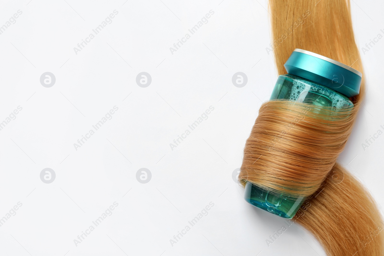 Photo of Bottle wrapped in lock of hair on white background, top view with space for text. Natural cosmetic product