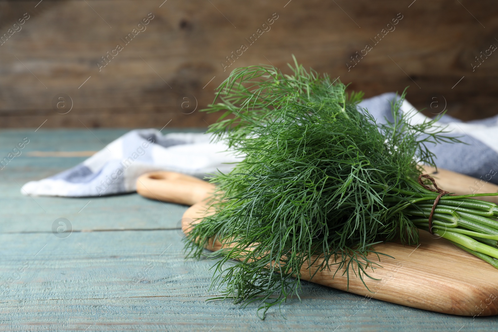 Photo of Bunch of fresh dill on light blue wooden table, space for text