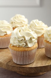 Photo of Tasty cupcakes with vanilla cream on pink wooden table, closeup