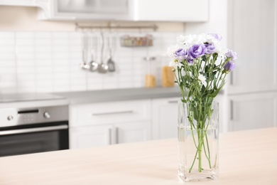 Photo of Vase with beautiful flowers on table in kitchen interior. Space for text