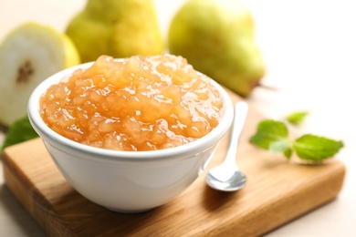Photo of Tasty homemade pear jam and fresh fruits on wooden table, closeup
