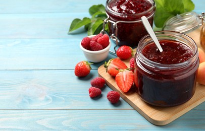 Photo of Jars with different jams and fresh berries on light blue wooden table. Space for text