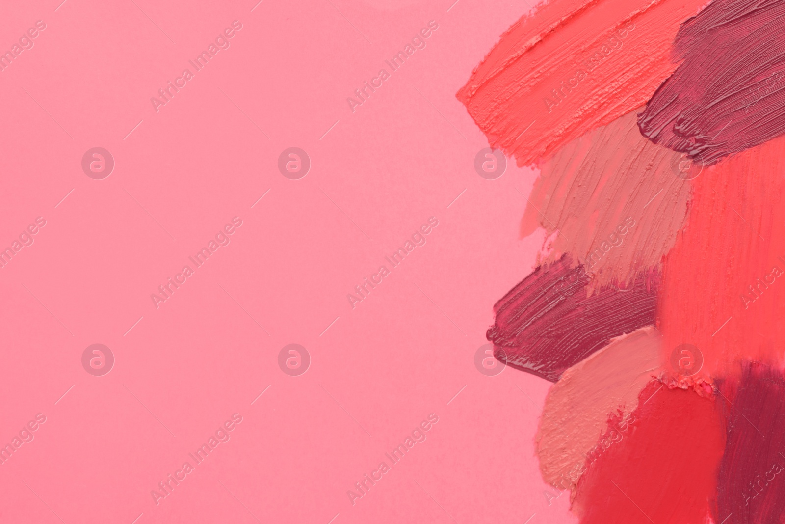 Photo of Smears of different beautiful lipsticks on pink background, top view. Space for text