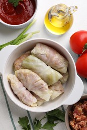 Uncooked stuffed cabbage rolls and ingredients on table, flat lay