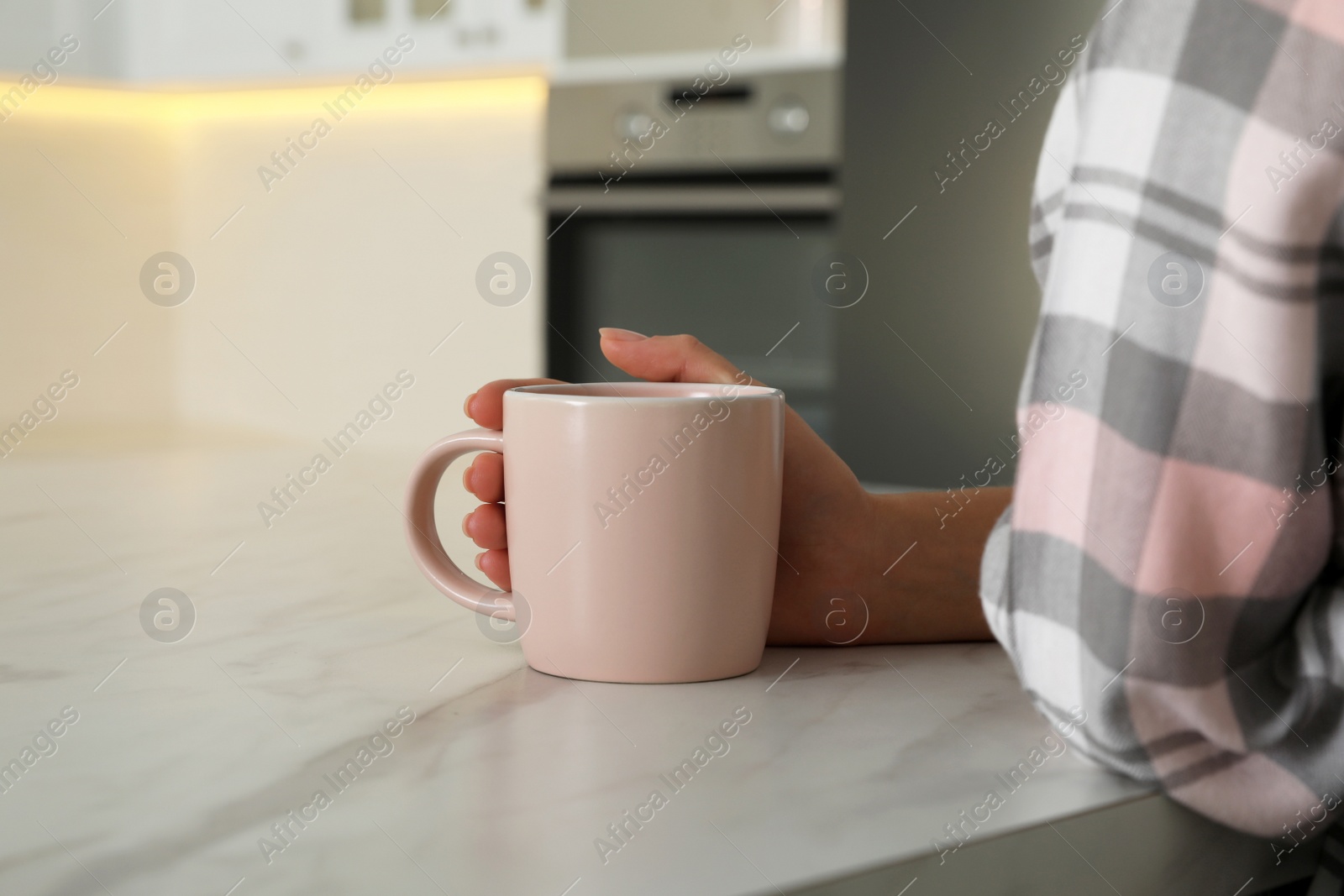 Photo of Woman with pink cup at table indoors, closeup