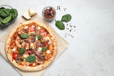 Tasty pizza with anchovies and ingredients on white table, flat lay. Space for text