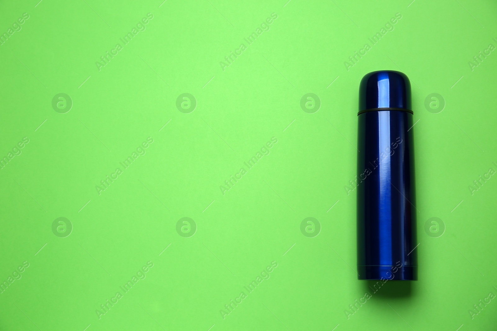 Photo of New modern thermos on green background, top view. Space for text