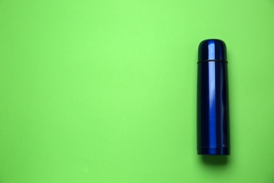 Photo of New modern thermos on green background, top view. Space for text