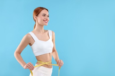 Photo of Slim woman measuring waist with tape on light blue background, space for text. Weight loss