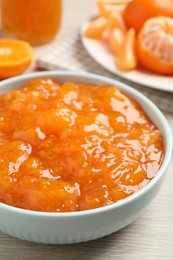 Photo of Delicious tangerine jam on wooden table, closeup