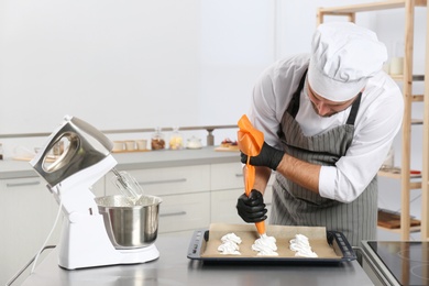 Photo of Pastry chef preparing meringues at table in kitchen