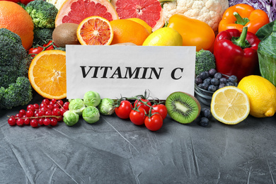 Photo of Different products and card with phrase VITAMIN C on grey table