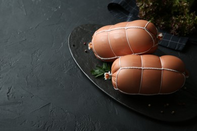 Photo of Tasty boiled sausages on dark textured table, above view. Space for text