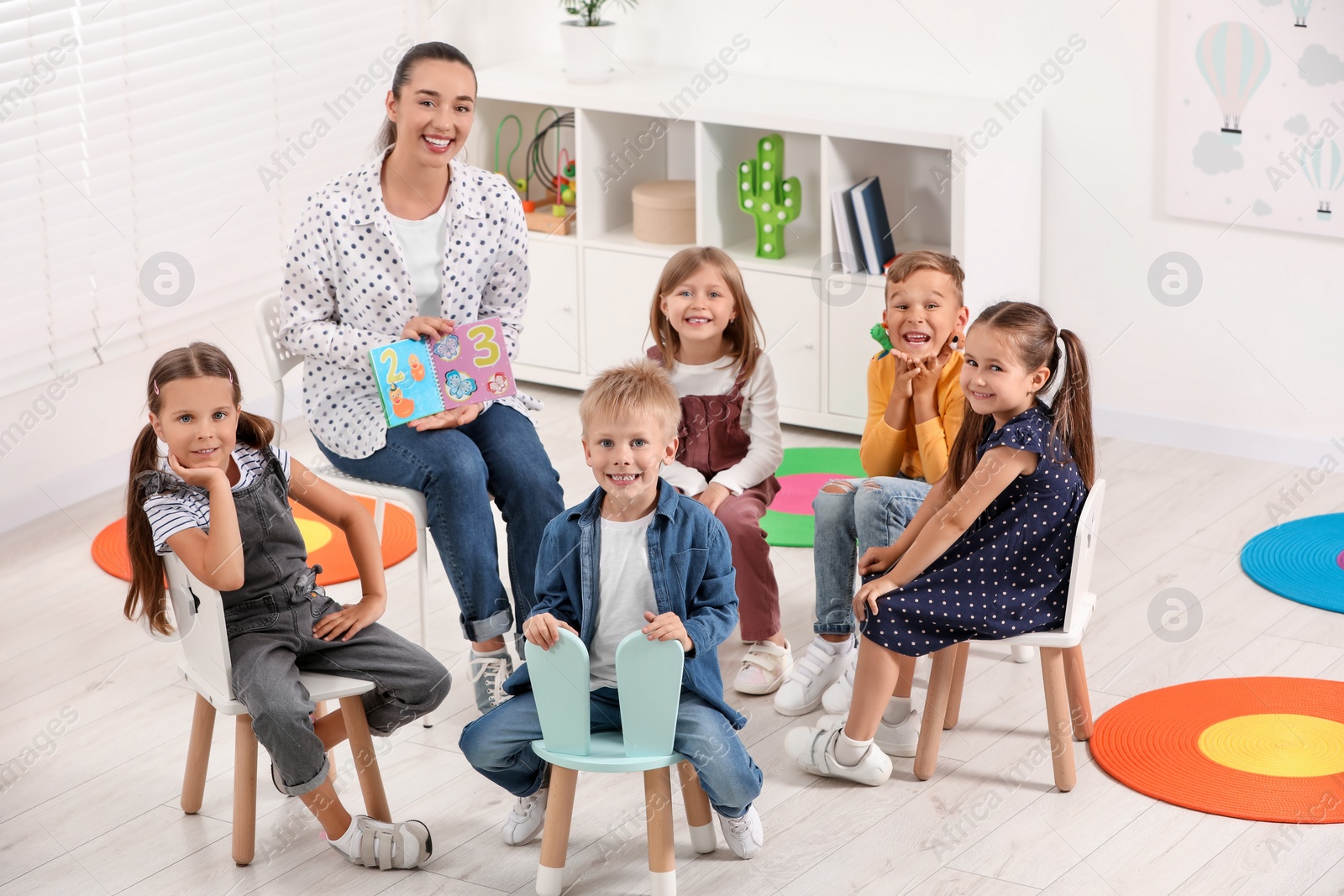 Photo of Nursery teacher and group of cute little children learning numbers in kindergarten. Playtime activities