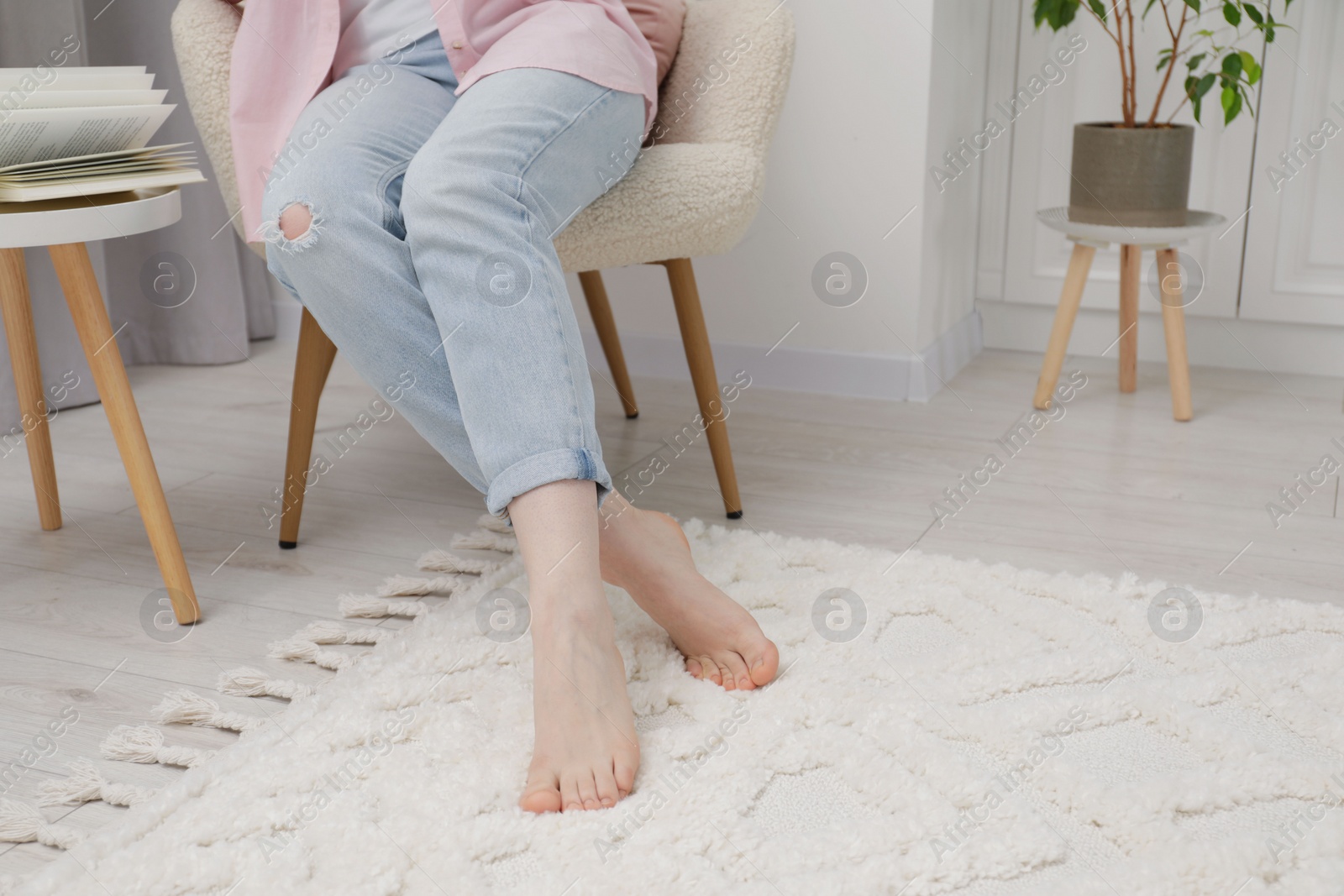 Photo of Woman sitting on armchair near beige carpet indoors, closeup. Space for text