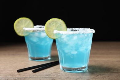 Photo of Refreshing light blue cocktail on wooden table