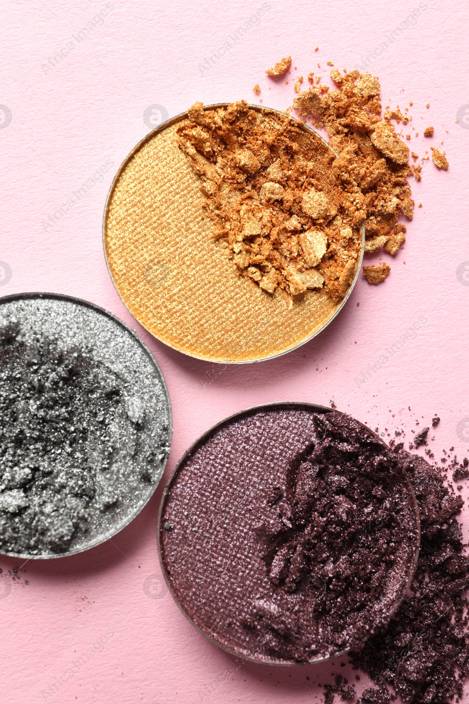 Photo of Different crushed eye shadows on pink background, flat lay