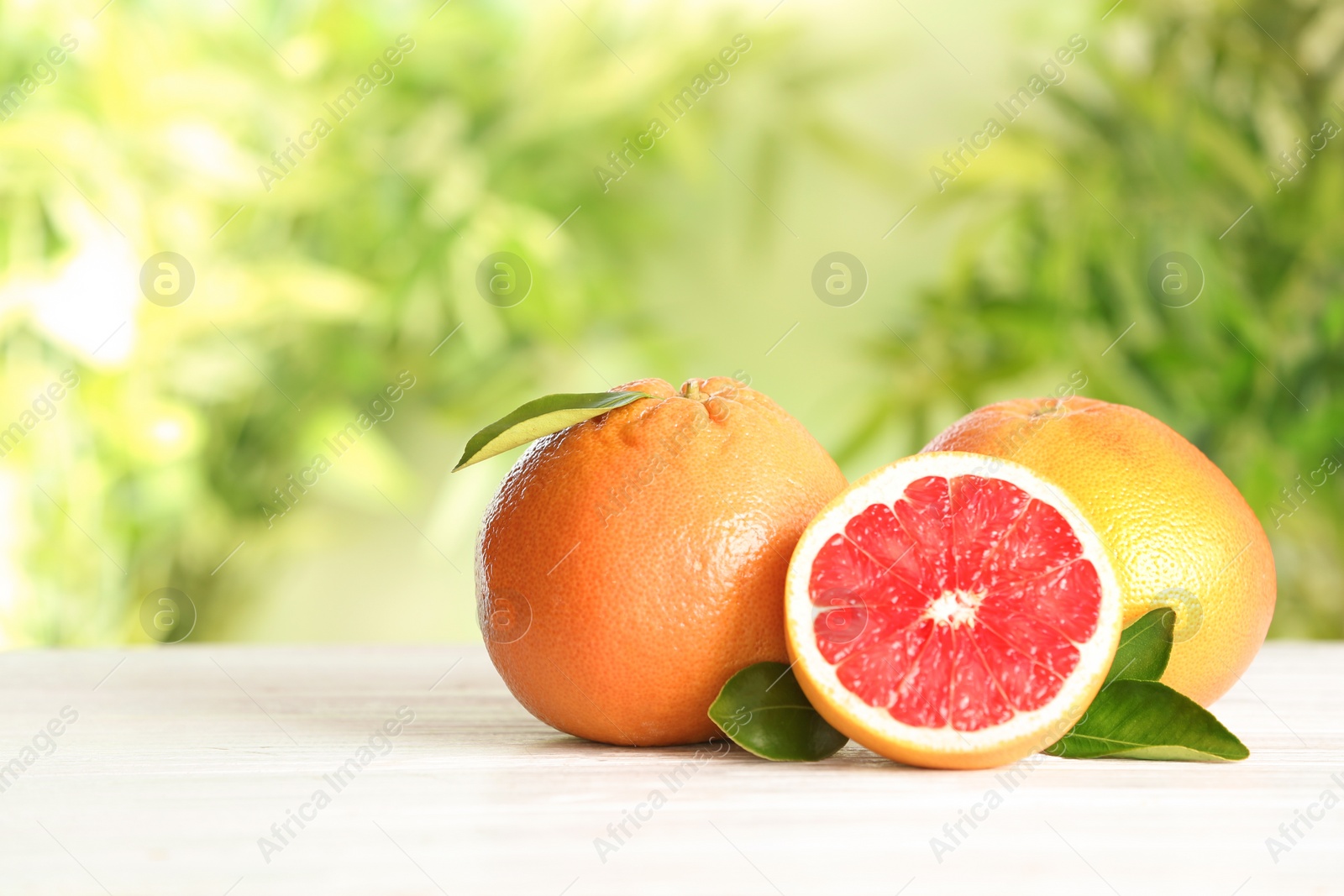 Photo of Yummy grapefruits on wooden table against blurred background. Space for text