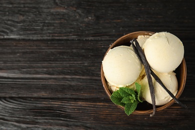 Delicious vanilla ice cream with mint and pods on wooden table, top view. Space for text