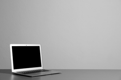 Photo of Modern laptop with blank screen on table against gray background