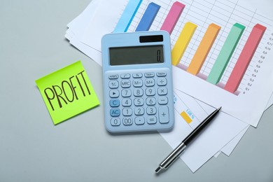 Photo of Sticky note with word Profit, calculator and diagram on light grey background, flat lay