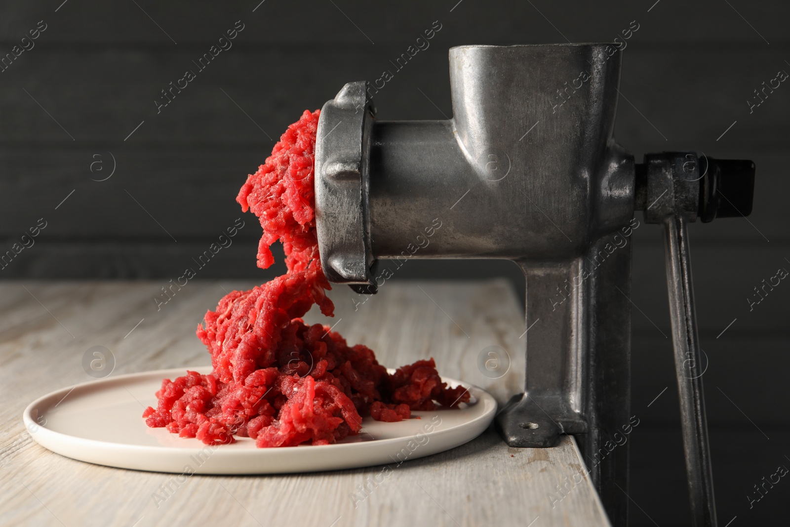 Photo of Metal meat grinder with beef mince on light wooden table