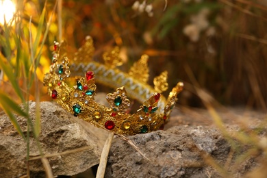 Photo of Beautiful golden crown on stone outdoors, closeup. Fantasy item