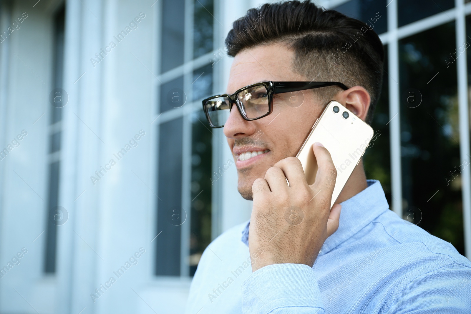 Photo of Man talking on modern mobile phone outdoors