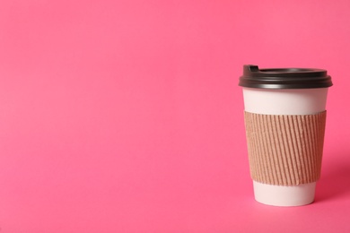 Takeaway paper coffee cup with cardboard sleeve on pink background. Space for text