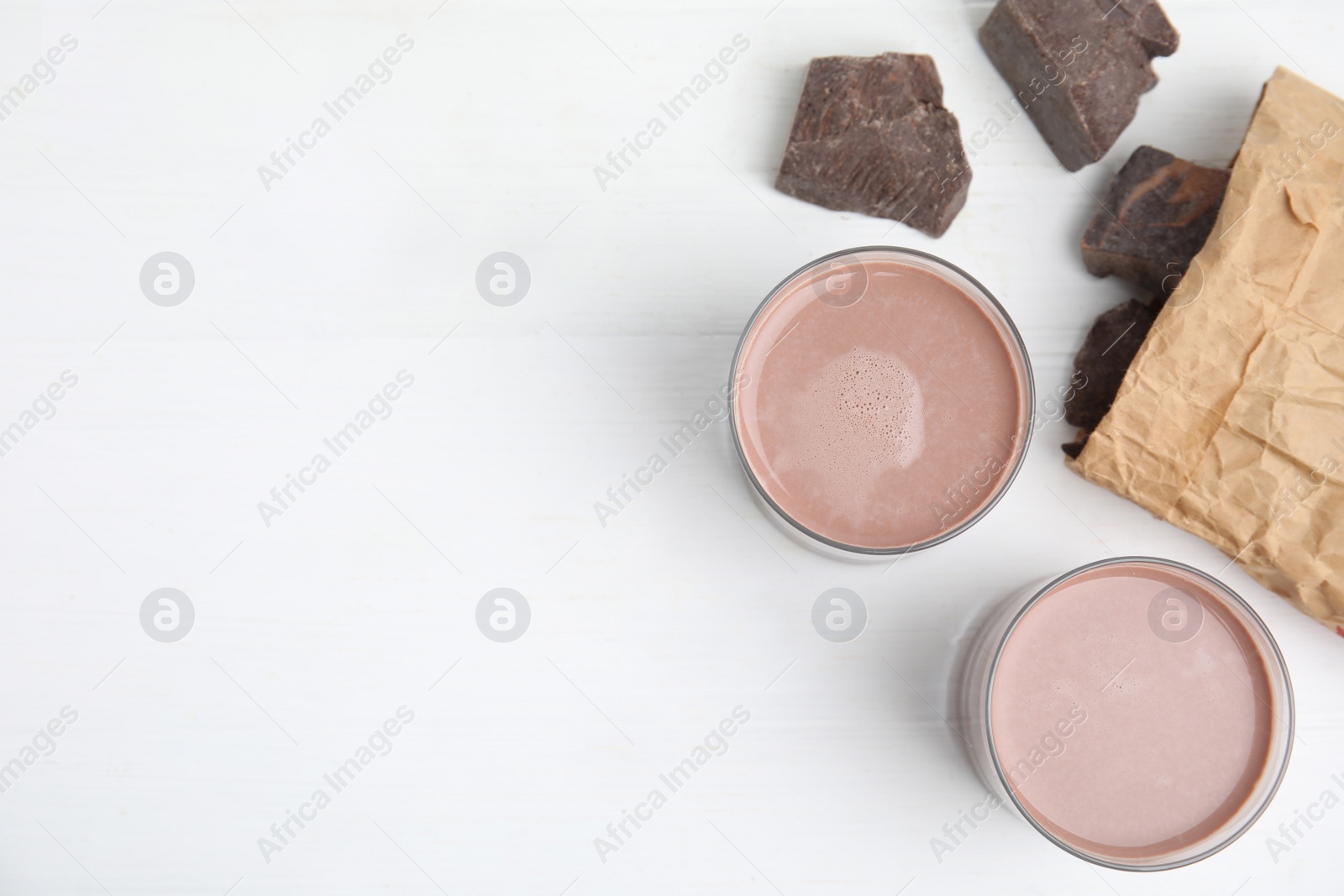 Photo of Delicious chocolate milk on white wooden table, flat lay. Space for text