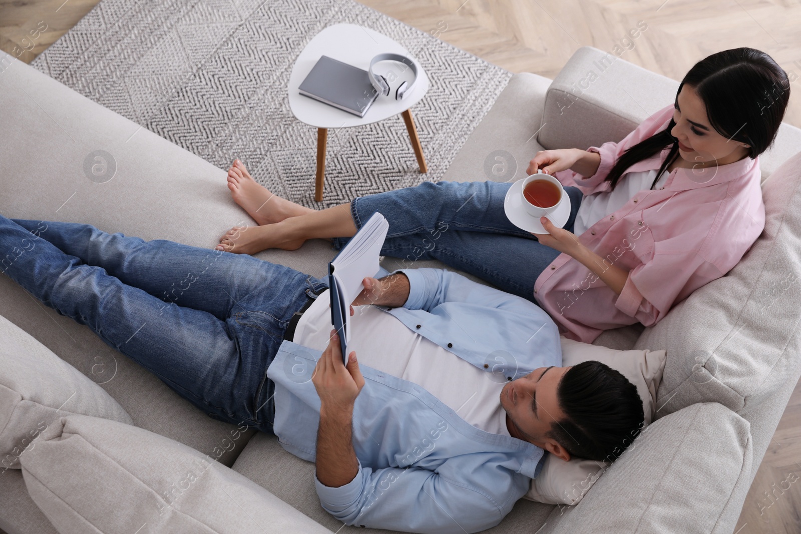 Photo of Couple resting on sofa in living room, above view