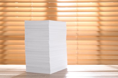 Photo of Stack of paper sheets on wooden table. Space for text