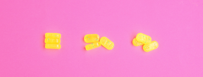 Tasty lemon drops on pink background, flat lay