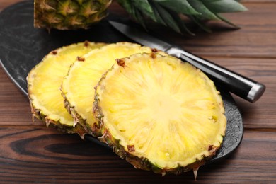 Photo of Pieces of tasty ripe pineapple on wooden table, closeup