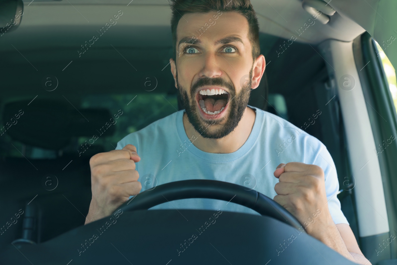 Photo of Stressed angry man in driver's seat of modern car, view through windshield