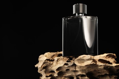 Photo of Luxury men`s perfume in bottle against black background, space for text