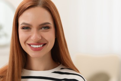 Photo of Portrait of beautiful young woman with red hair indoors. Attractive lady smiling and looking into camera. Space for text
