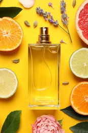 Flat lay composition with bottle of perfume and fresh citrus fruits on yellow background