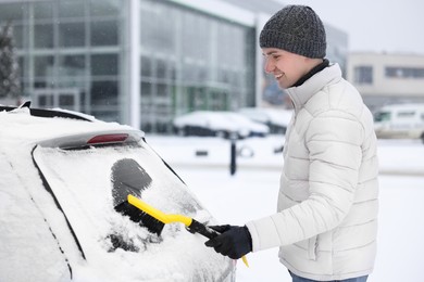 Photo of Man cleaning snow from car window outdoors