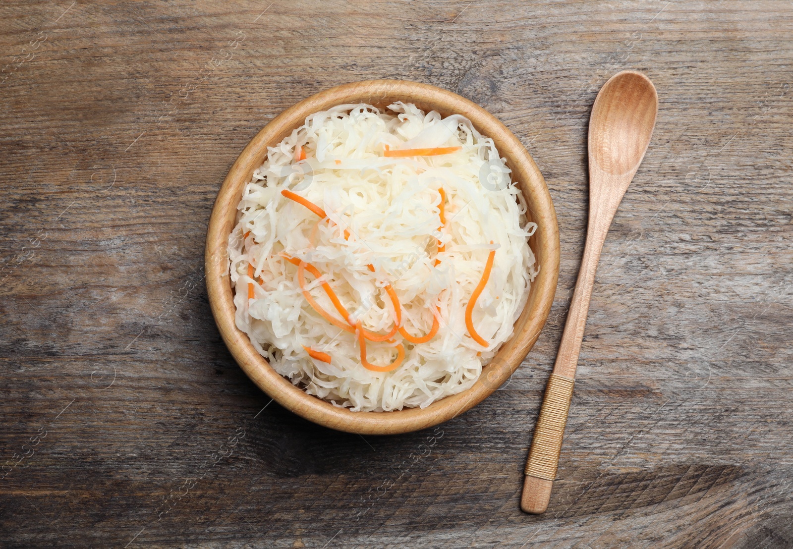 Photo of Tasty fermented cabbage on wooden table, flat lay