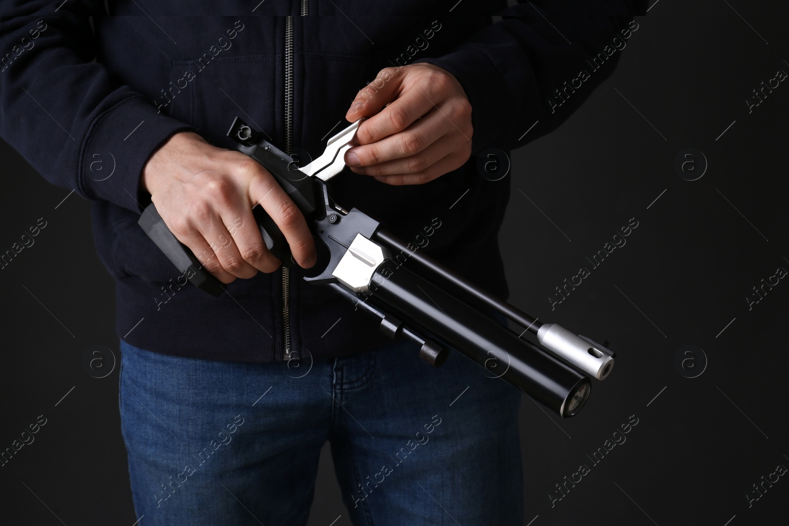 Photo of Gun shooting sport. Man holding standard pistol on dark background, closeup